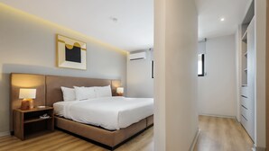 A modern hotel room with a large bed, bedside lamps, a framed artwork, and an air conditioning unit. - w Deluxe 1BR w/ AC in the Heart of Roma Sur (Mexico City)
