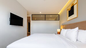 A hotel room with a bed, a TV mounted on the wall, a bedside lamp, and a framed picture. - w Deluxe 1BR w/ AC in the Heart of Roma Sur (Mexico City)