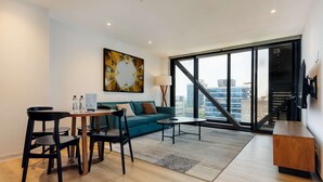A modern living room with a sofa, coffee table, and chairs, a painting on the wall, and a large window with a city view. - w Amazing 1BR w/ AC in the Heart of Roma Sur (Mexico City)