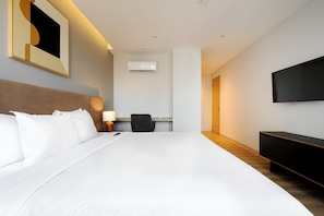A hotel room with a large bed, a desk with a chair, a TV mounted on the wall, and an air conditioning unit. - w Amazing 1BR w/ AC in the Heart of Roma Sur (Mexico City)