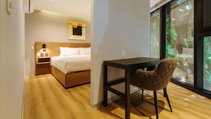 A bedroom with a bed, bedside table, lamp, and a view of greenery through large windows. - w Beautiful 2BR w AC in the Heart of Roma Sur (Mexico City)