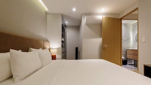 A hotel room with a large bed, a bedside table with a lamp, a wardrobe, and an air conditioning unit. - w Beautiful 2BR w AC in the Heart of Roma Sur (Mexico City)