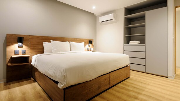 A bedroom with a wooden bed, bedside lamps, a wardrobe, and an air conditioning unit. - w Elegant 2BR w AC in the Heart of Roma Sur (Mexico City)