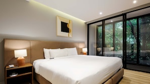 A modern hotel room with a large bed, bedside tables, a nightstand, a framed picture on the wall, and a large window with a view of trees. - w Elegant 2BR w AC in the Heart of Roma Sur (Mexico City)