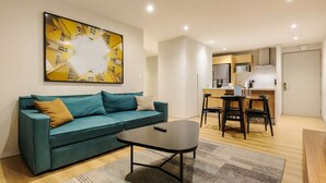 A modern living room with a teal sofa, a coffee table, and a dining area with a small table and chairs. - w Elegant 2BR w AC in the Heart of Roma Sur (Mexico City)