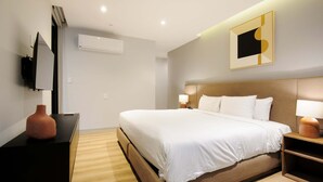 A modern hotel room with a large bed, bedside lamps, a flat-screen TV, and a wall-mounted air conditioner. - w Elegant 2BR w AC in the Heart of Roma Sur (Mexico City)