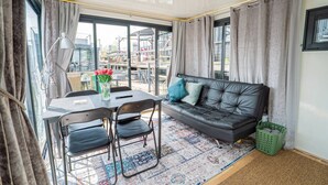 En moderne stue med sofa, stole, et bord og udsigt til byen.