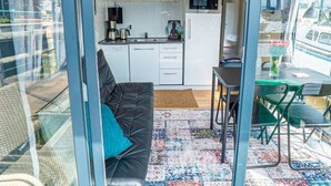 Et moderne interiør med en sofa, et spisebord og et køkken, der kan ses igennem en glasdør.