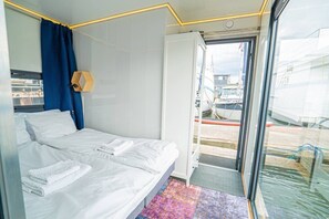 Ein Zimmer mit Bett, einem Vorhangfenster und Blick auf Boote.