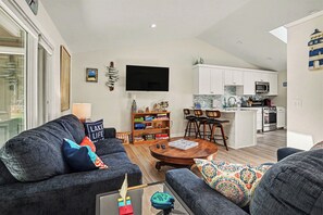 A modern living room with a sofa, coffee table, and a bookshelf. - Bright Condo with Fire pit—Near Beach & Town (Douglas)