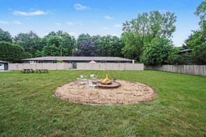 A backyard with a circular fire pit, picnic table, and chairs. - Bright Condo with Fire pit—Near Beach & Town (Douglas)
