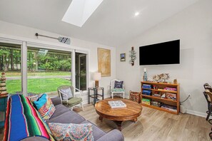 Ein Wohnzimmer mit Sofa, Couchtisch, Bücherregal und einem an der Wand befestigten Fernseher.