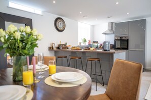 A modern kitchen with a central island, bar stools, and a dining table set for four. - 2-Bed Retreat- Gated Parking- Work, Recharge, Stay (Worksop)