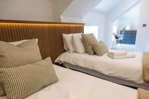 Un dormitorio con cama, almohadas, cabecera y vista a un pasillo.