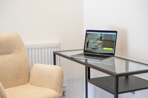 A laptop on a glass table with a beige chair beside it. - 2-Bed Retreat- Gated Parking- Work, Recharge, Stay (Worksop)