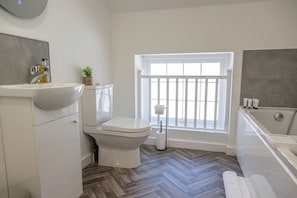 Un baño con inodoro, lavabo, ventana y bañera.