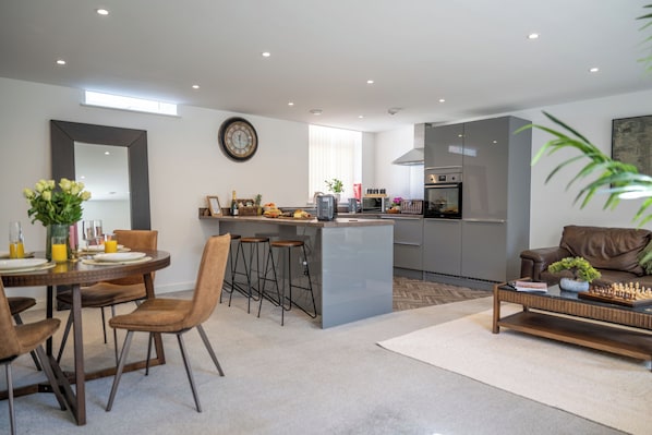 A modern kitchen with a central island, bar stools, and a dining area with a round table and chairs.