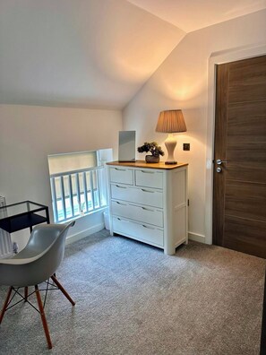 A room with a white dresser, a lamp, a chair, and a door. - 2-Bed Retreat- Gated Parking- Work, Recharge, Stay (Worksop)