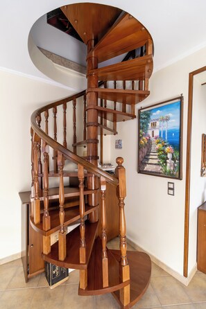 Un escalier en colimaçon en bois, avec une peinture représentant un paysage côtier accrochée au mur.