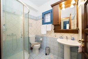 Uma casa de banho com cabine de duche em vidro, sanita, lavatório com espelho em cima e armário de medicamentos com moldura azul.