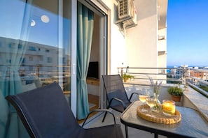 A balcony with a table, chairs, a TV, and a view of the sea. - Boho Dream 1 | Stylish Retreat Between Ada Bojana & Ulcinj (Ulcinj)