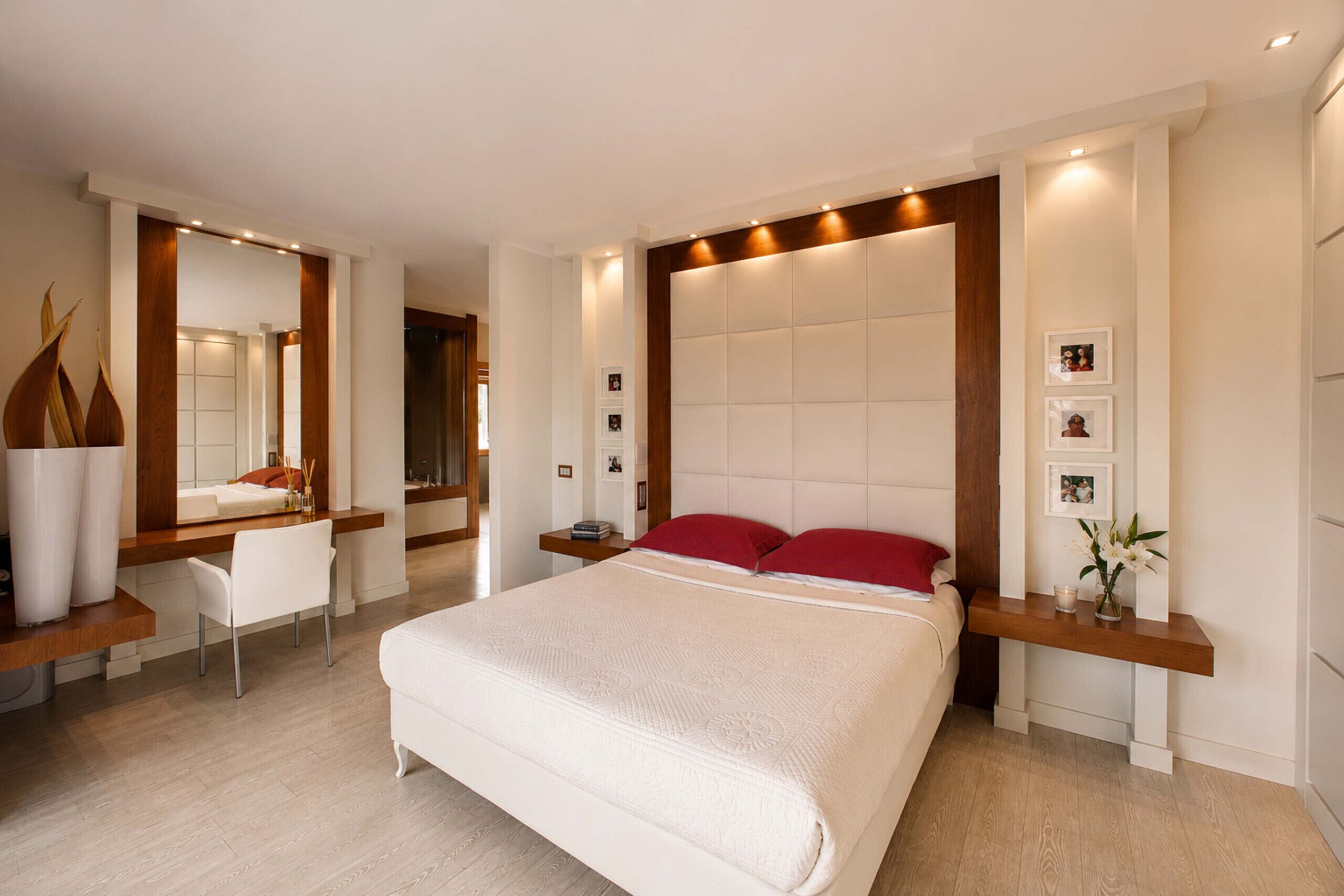 A modern bedroom with a large bed, a desk, and a mirror.