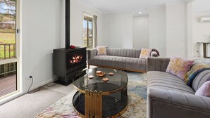 Ein modernes Wohnzimmer mit einem schwarzen Kaminofen, einem grauen Sofa und einem Glastisch.