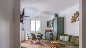 A modern kitchen with green cabinets, a dining area with a round table and chairs, and a sofa with cushions. - Town house + Parking and garden 5 min Bretonneau Tours center (Tours)