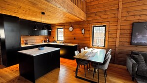 Een moderne keuken met houten wanden, een centraal eiland en een zithoek met tafel en stoelen.