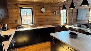Eine moderne Küche mit Holzwänden, einem großen Fenster und einem Essbereich mit Tisch und Stühlen.