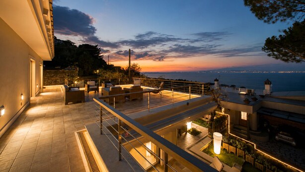 Una terraza en la azotea con mobiliario exterior, vistas al mar y un diseño arquitectónico bien iluminado.