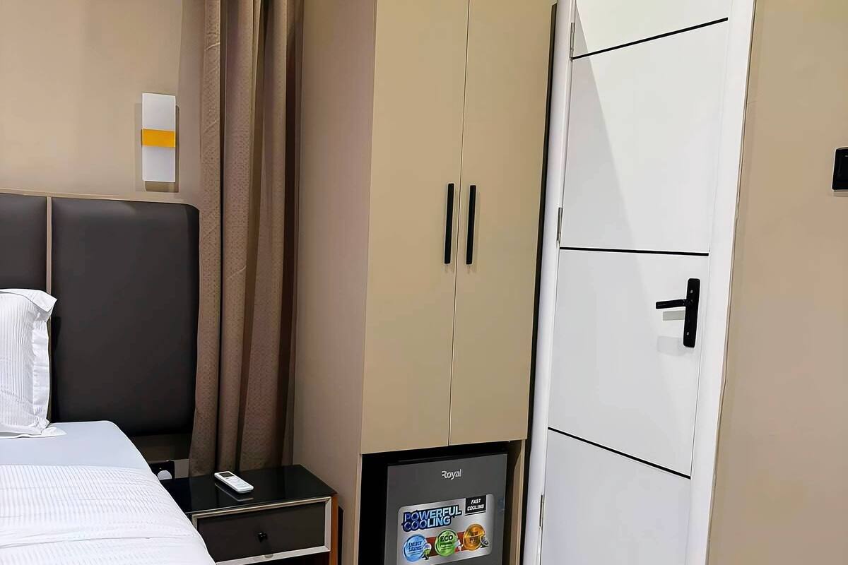 A hotel room with a bed, a wardrobe, a small TV, and a door.