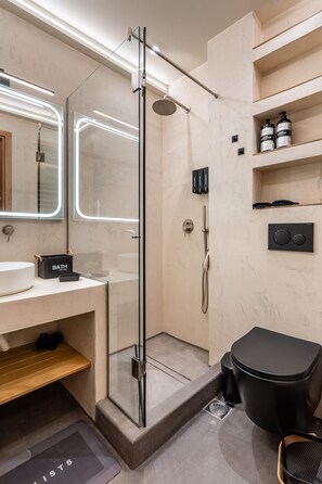 Casa de banho moderna com cabine de duche em vidro, toucador com lavatório e estantes embutidas.