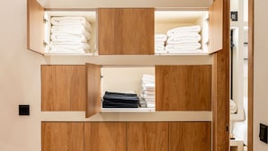 A wooden wardrobe with multiple shelves and doors, some with folded towels. - Apex B1 - Modern City Stay in Central Pangrati (Athens)