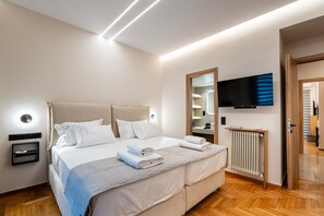 A modern hotel room with a large bed, bedside tables, a flat-screen TV, a mirror, and a radiator. - Apex B1 - Modern City Stay in Central Pangrati (Athens)