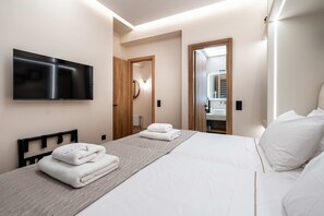 A hotel room with a bed, a TV, a mirror, and a bathroom visible through an open door. - Apex B1 - Modern City Stay in Central Pangrati (Athens)