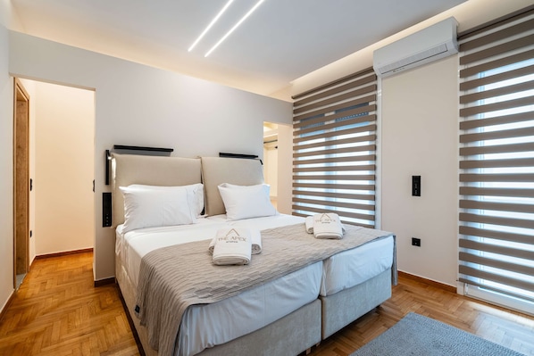 Ein modernes Schlafzimmer mit einem Bett, Nachttischen, einer Klimaanlage und einem Fenster mit Jalousien.