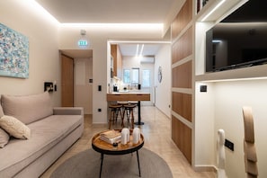 Ein modernes Wohnzimmer mit einer Couch, einem Couchtisch und einer Küche im Hintergrund.