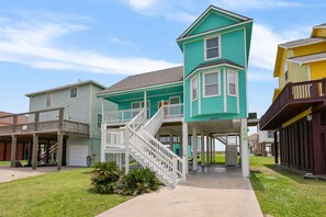 A two-story house with a front porch, a staircase leading to the second floor, and a garage. - Sol Searcher - Close to the beach, gulf view, easy beach access! (Crystal Beach)