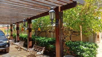 Uma área de estar ao ar livre coberta, com bancos e luminárias de rua.