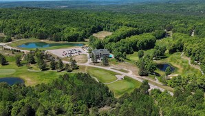 En vy över en golfbana från ovan, med ett klubbhus, flera dammar och omgivande skogsområden.