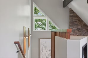 Eine Treppe mit einer Steinwand, einem Holzgeländer und einem gerahmten Kunstwerk.