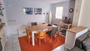 Un espace de vie compact comprenant un coin repas, une kitchenette et un petit coin salon.