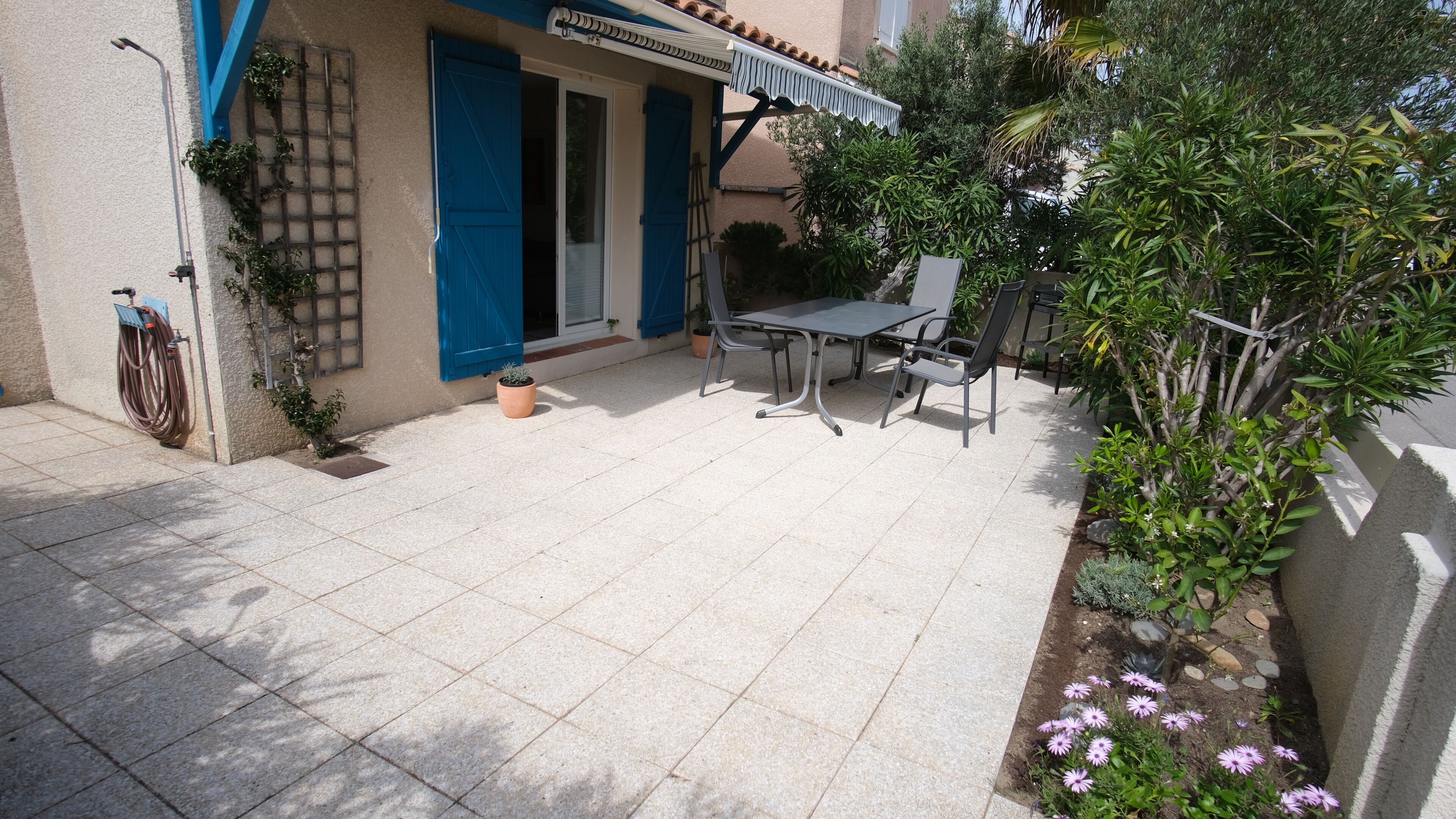 Eine Terrasse mit Tisch, Stühlen, einem Fahrrad und Topfpflanzen.