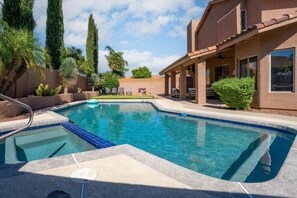 Ein Schwimmbecken mit einer gefliesten Kante, Liegestühlen und einer überdachten Terrasse.