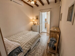 Un dormitorio con cama, cómoda, espejo y puerta que da a un baño.