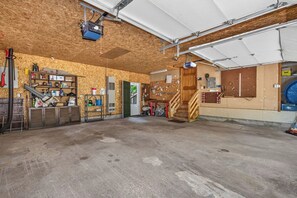 En rummelig garage med trægulv, arbejdsbord og forskelligt værktøj og udstyr.