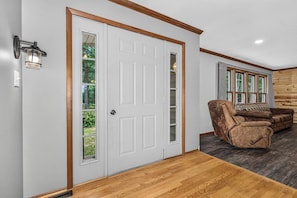 A room with a white door, a brown leather recliner, and a wooden floor. - Balsam Lodge, our newly renovated addition to Hillcrest Cottages. (St.Germain)