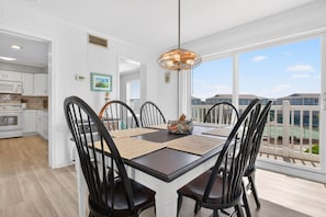 A dining area with a table, chairs, and a hanging light fixture. - Salt & Sound -  Top Floor Water Views - Walk to Beach - 3 Bedroom 2 Bathroom (Ocean Isle Beach)
