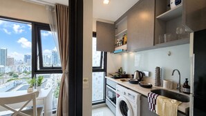Eine moderne Küche mit Waschmaschine, eine Essecke mit Ausblick und ein Stadtbild im Fenster zu sehen.